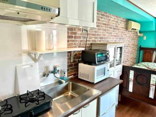 a kitchen with a sink and a microwave at ラフォレ１０１　新宿から13分のくつろげるお部屋 in Tokyo