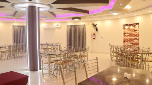 een kamer met tafels en stoelen en een podium bij Pradee Queen Resorts in Tiruvallūr
