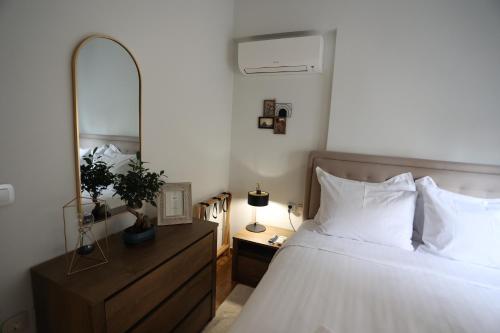 - une chambre avec un lit avec un miroir et une commode dans l'établissement LA Larissa Luxury Apartments Thetis, à Larissa