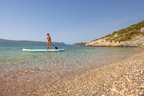 a man standing on a paddle board in the water at Chariclea Villas Retreat in Samos