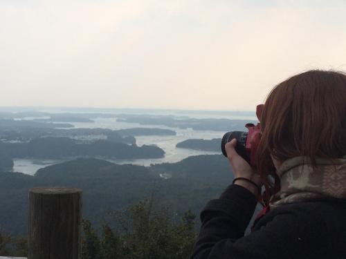 a woman taking a picture of a river with a camera at 伊勢ゲストハウス紬舎-Ise Guesthouse Tsumugiya- in Ise