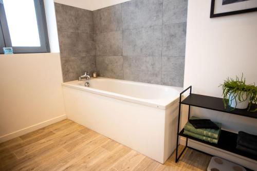 La salle de bains est pourvue d'une baignoire blanche et d'un mur en carrelage. dans l'établissement Appartement Duplex en Centre-Ville de Cambrai - 110m2, à Cambrai