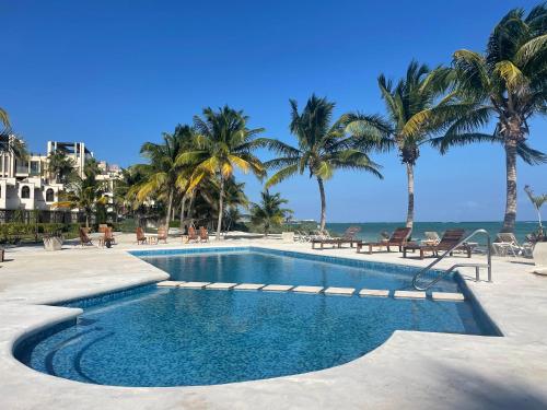 a swimming pool with palm trees and the ocean at VR CLUB Tulum Riviera in Tulum