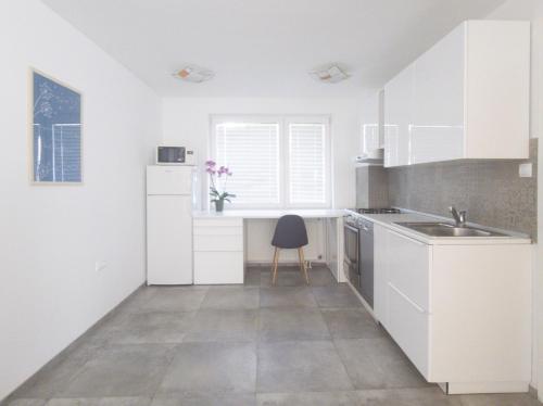 a kitchen with white cabinets and a sink and a chair at Harmony House Velenje in Velenje