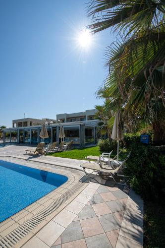 a resort with a pool and chairs and a building at Hydramis Palace Beach Resort in Georgioupolis