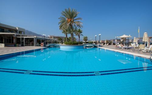 a large blue swimming pool with a palm tree in the background at Hydramis Palace Beach Resort in Georgioupolis