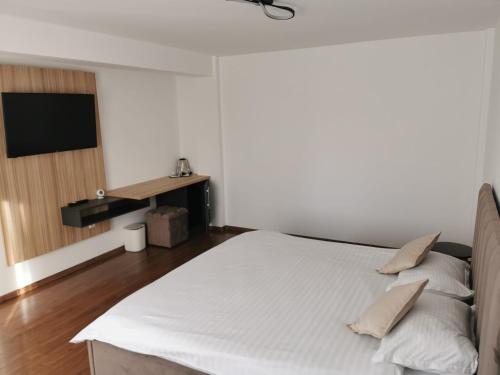 a bedroom with a white bed and a television at Belvedere Restaurant & Rooms in Topliţa
