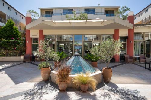 a building with a swimming pool in a courtyard with potted plants at Hydramis Palace Beach Resort in Georgioupolis