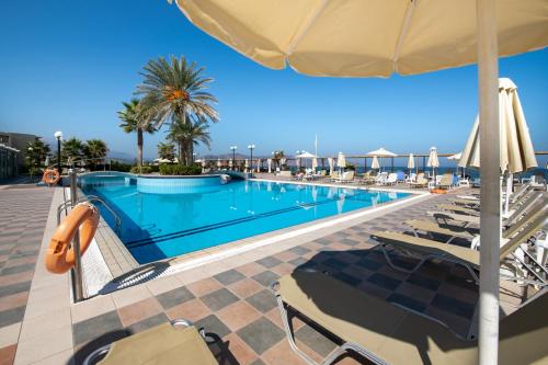 a swimming pool with chairs and an umbrella at Hydramis Palace Beach Resort in Georgioupolis
