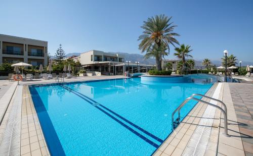 a large swimming pool in a resort with a palm tree at Hydramis Palace Beach Resort in Georgioupolis