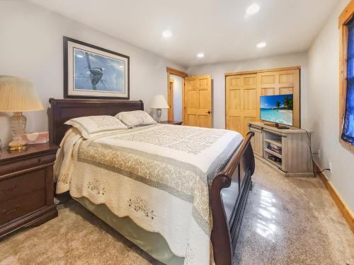 1 dormitorio con 1 cama y TV de pantalla plana en Anchors Away Cottage on Big Spirit Lake, en Orleans