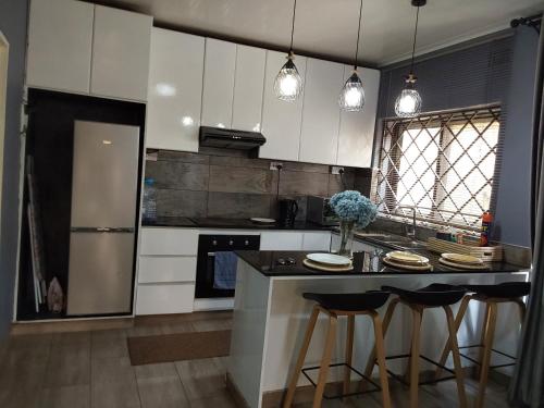 a kitchen with white cabinets and a island with bar stools at Rena Apartment in Lilongwe