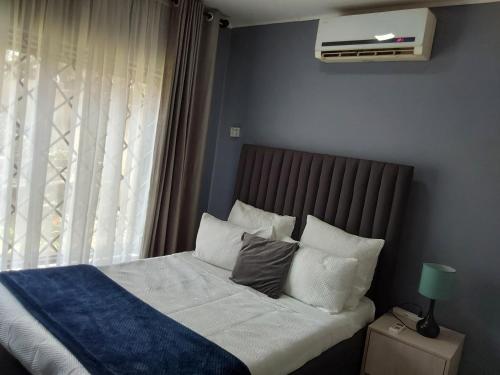 a bed with white sheets and pillows next to a window at Rena Apartment in Lilongwe