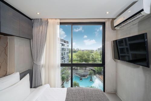 a bedroom with a large window with a view of a pool at Tropics Kamala 2BR Apartment CTG B605-6 in Kamala Beach