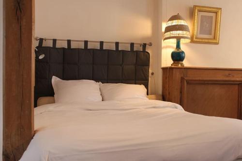 uma grande cama branca com uma cabeceira preta e um candeeiro em Appartement -Le Clos- Cellier de l'abbaye em Vézelay