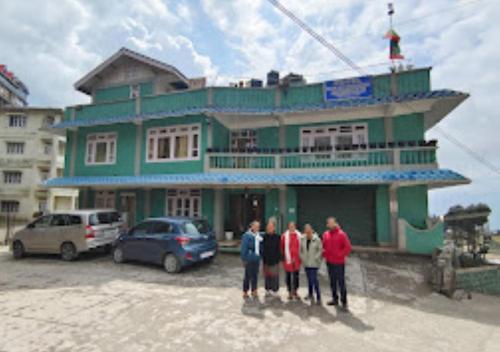 a group of people standing in front of a green building at HOTEL MON KYIMOJONG ARUNACHAL PRADESH in Tawang