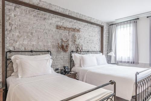 two beds in a room with a brick wall at Thames Valley Khao Yai - SHA Plus in Mu Si