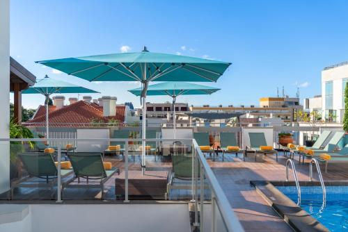 um pátio com cadeiras, um guarda-sol e uma piscina em Hotel Madeira no Funchal