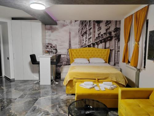 a bedroom with a yellow bed and a desk at Hedonic Wellness Apartmani in Niš