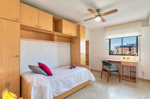 een slaapkamer met een bed, een bureau en een raam bij LUMINOSO APARTAMENTO/ 5 MINUTOS DE LA PLAYA in Málaga