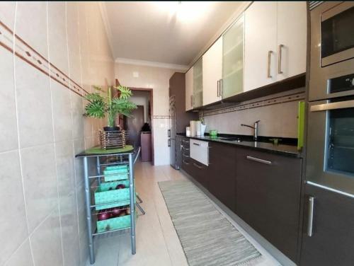uma cozinha com armários castanhos, um lavatório e um balcão em Apartamento frente ao mar em Lavra