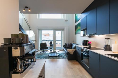 a kitchen with blue cabinets and a living room at Isla Homes - Suite, Supermarket & Alko in Tampere