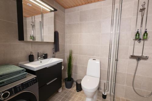 a bathroom with a toilet and a sink and a shower at Isla Homes - Suite, Supermarket & Alko in Tampere