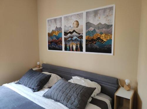 a bedroom with a bed with four pictures on the wall at Logis Dans La Place Appartement in Thouarcé