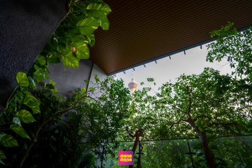 Ceylonz Suites KLCC Rooftop Infinity Pool KL Tower View في كوالالمبور: مبنى عليه لافتة وردية اللون أمام الأشجار