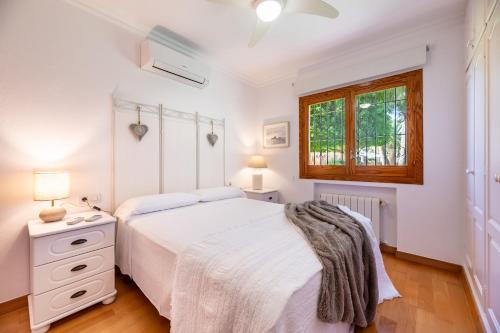 a white bedroom with a bed and a window at Villa Can Raco Ibiza in Sant Rafael de Sa Creu