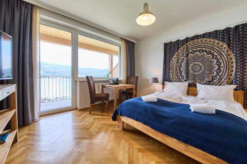 a bedroom with a blue bed with a large window at Hermitage Vital Hotel in Maria Wörth