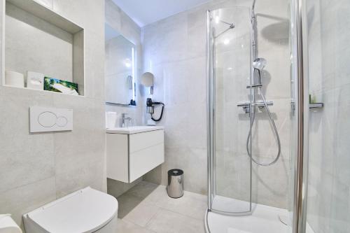 a white bathroom with a shower and a toilet at Hermitage Vital Hotel in Maria Wörth