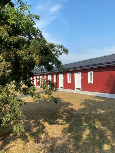 a row of red and white buildings with a tree at Bedinge Golfklubb hotell in Beddinge Strand