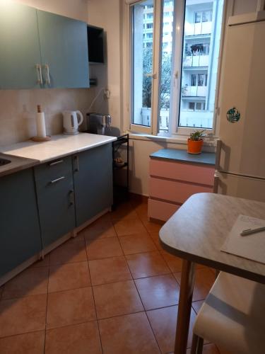 cocina con armarios azules, mesa y ventanas en Warta Piastowskie Apartament, en Poznan
