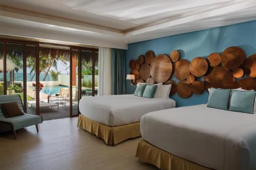 a bedroom with two beds and a blue wall at Azul Villa Esmeralda - Gourmet All Inclusive by Karisma in Puerto Morelos