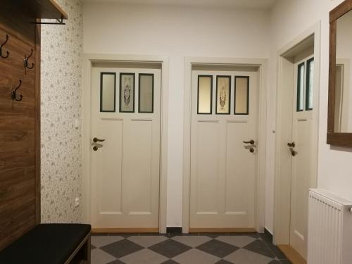 two doors in a room with a checkered floor at Apartmány Na Staré poště in Jimramov