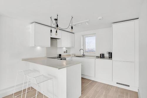 una cocina blanca con armarios blancos y fregadero en Radiant Chelsea Flat with City View, en Londres