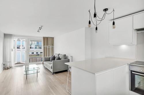 een witte keuken en een woonkamer met een bank bij Radiant Chelsea Flat with City View in Londen