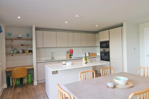 a kitchen with white cabinets and a table and chairs at Stylish estuary view apartment in Padstow