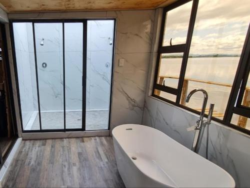 a bathroom with a bath tub and a large window at Tshifaro Gardens in Thohoyandou