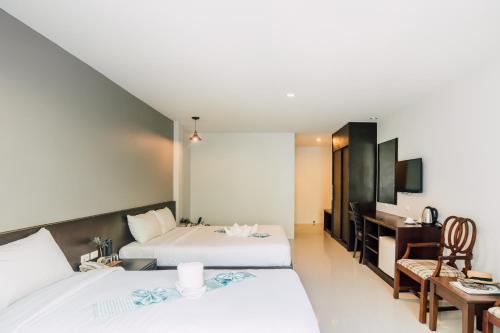 um quarto de hotel com duas camas e uma secretária em Harvest House em Praia de Aonang
