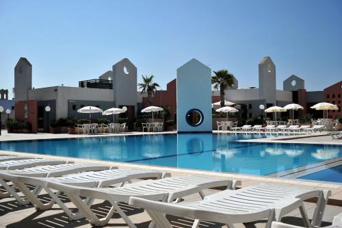 una piscina con tumbonas blancas frente a un edificio en The St. George’s Park Hotel en San Julián