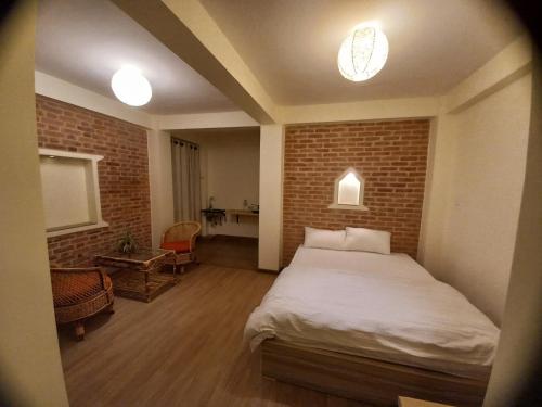 sypialnia z łóżkiem i ceglaną ścianą w obiekcie Hiti fusa w mieście Patan