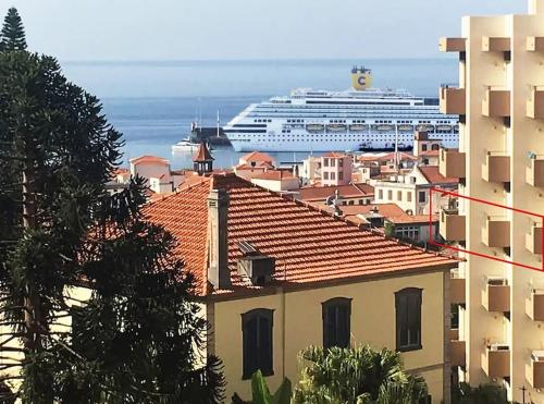 a cruise ship in the ocean behind a city with a building at Funchal downtown 5min Marina + 2 bedroom + parking in Funchal