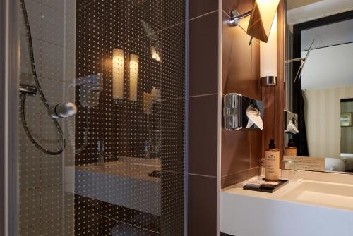 y baño con ducha y lavamanos. en Hotel Les Théâtres, en París