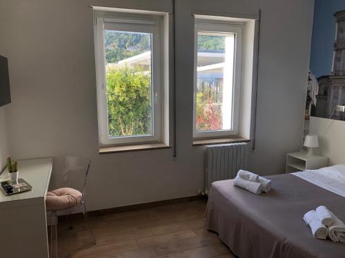 una camera da letto con 2 finestre, un letto e una scrivania di Hotel Porta Rivera a L'Aquila