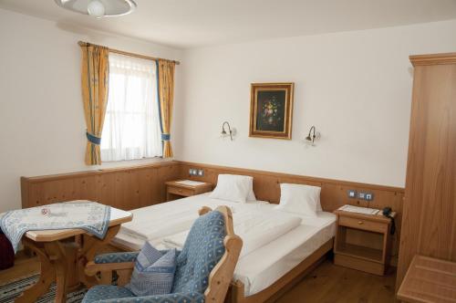 a bedroom with a bed, chair, desk and a window at Bloberger Hof in Salzburg