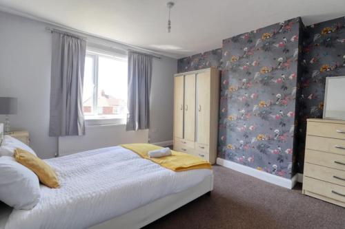 a bedroom with a large bed and a dresser at Highfield House cosy 4 bedroom in Scunthorpe