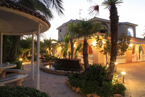 un cortile con palme e un edificio di Villa Iluminada con piscina y barbacoa cerca Playa a Elche