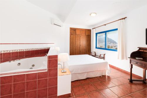 a bedroom with a tub and a bed and a piano at Hostal El Dorado in San José